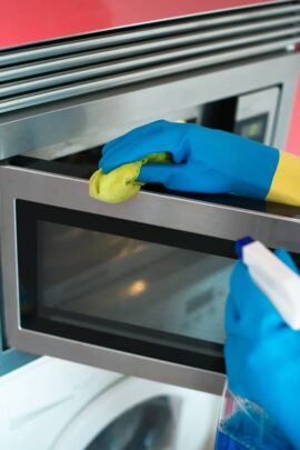 House cleaning. Woman is wiping microwave oven. Cleaning a microwave oven